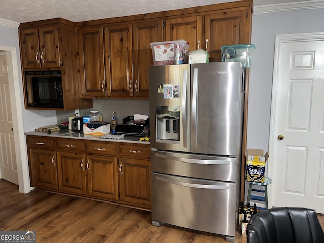 kitchen featuring black microwave, wood finished floors, light countertops, stainless steel refrigerator with ice dispenser, and crown molding