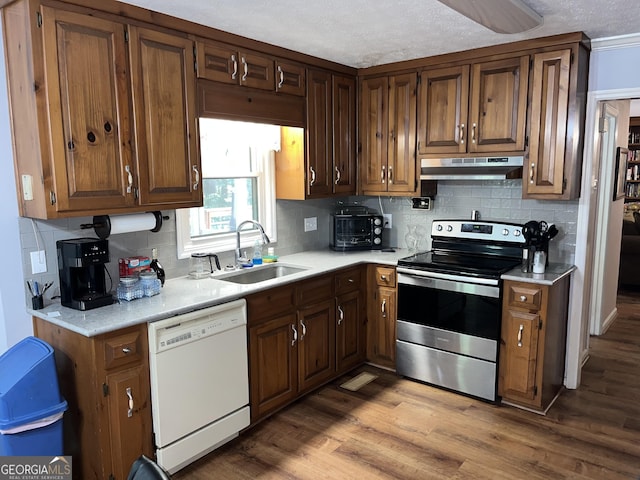 kitchen with white dishwasher, under cabinet range hood, a sink, light countertops, and stainless steel range with electric stovetop