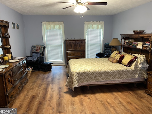 bedroom with a textured ceiling, ceiling fan, and wood finished floors