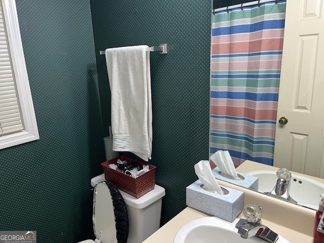 bathroom with curtained shower, a sink, and toilet