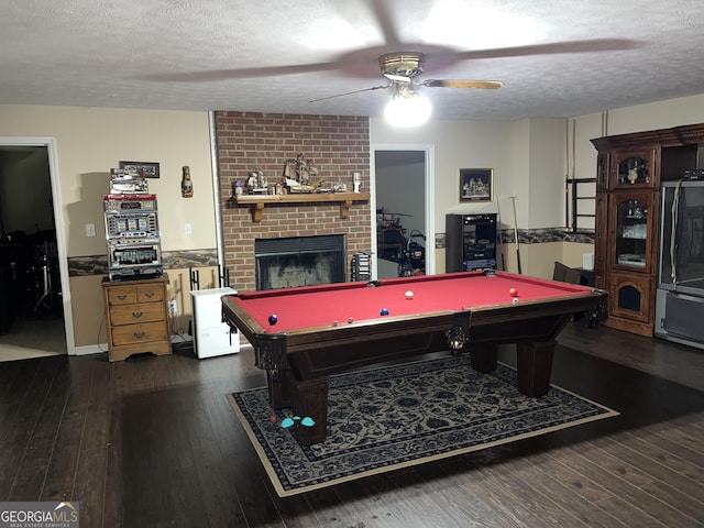 playroom featuring a textured ceiling, pool table, dark wood-type flooring, and a fireplace