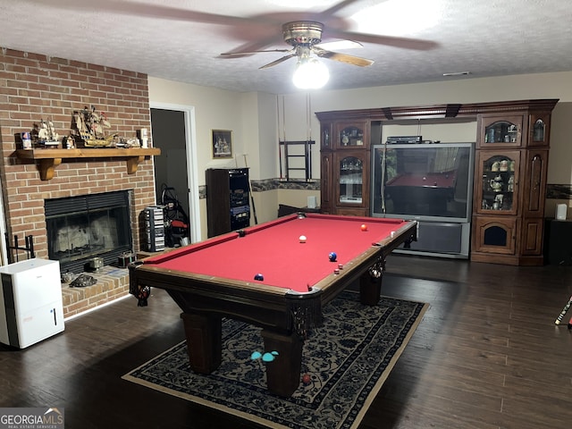 playroom featuring dark wood-type flooring, a fireplace, and a textured ceiling