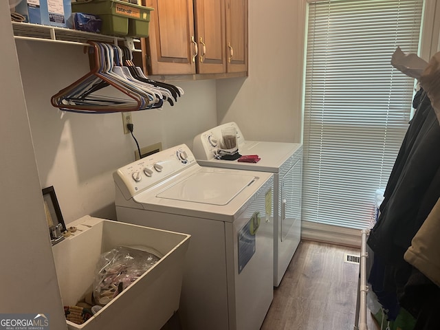 laundry area with washer and clothes dryer, visible vents, cabinet space, a sink, and wood finished floors