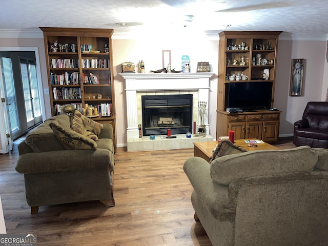 living area featuring a fireplace, ornamental molding, light wood-style floors, a textured ceiling, and baseboards