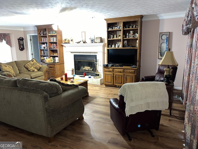 living area with ornamental molding, light wood-type flooring, a glass covered fireplace, and a textured ceiling