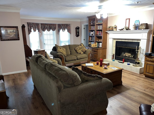 living room with ornamental molding, a fireplace, baseboards, and wood finished floors