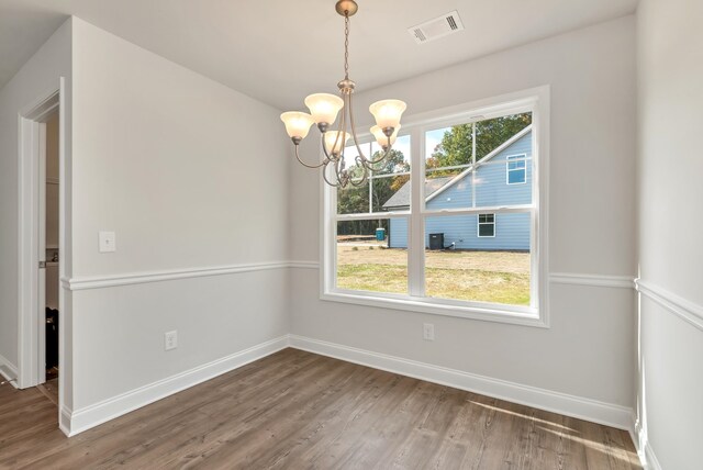 unfurnished dining area featuring a chandelier, plenty of natural light, and hardwood / wood-style floors