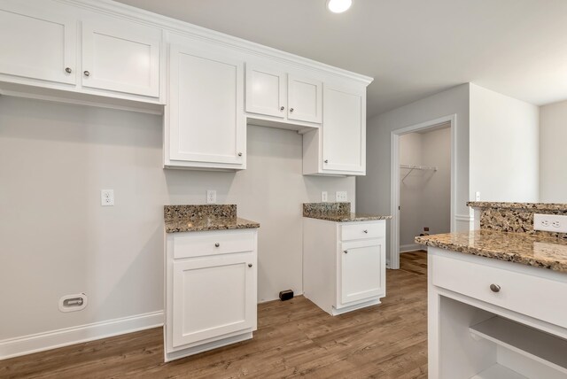 kitchen with dark stone countertops, white cabinetry, and wood-type flooring