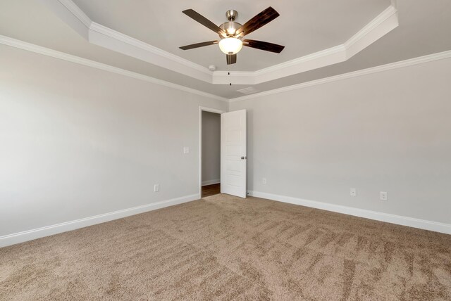 carpeted empty room featuring a tray ceiling, ceiling fan, and crown molding