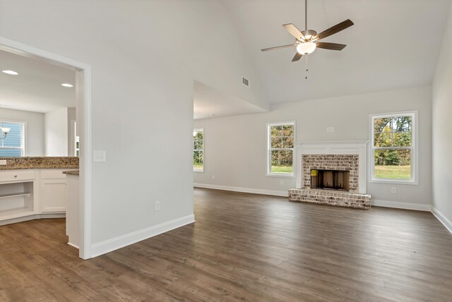 unfurnished living room with high vaulted ceiling, a healthy amount of sunlight, and dark hardwood / wood-style floors