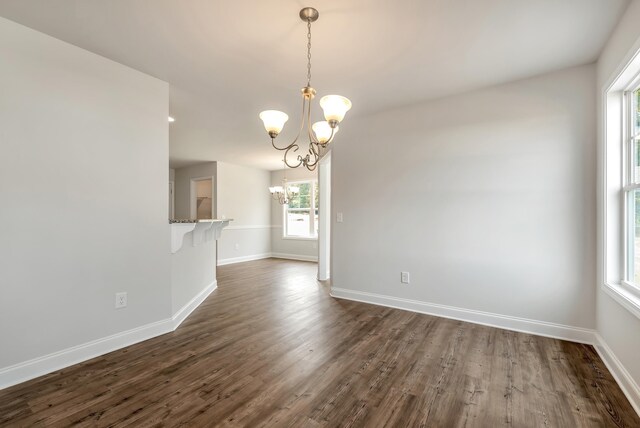 unfurnished room with an inviting chandelier and dark wood-type flooring