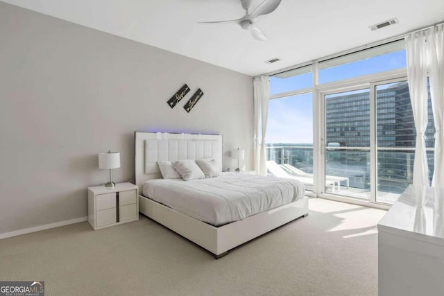 bedroom with visible vents, light colored carpet, and a wall of windows