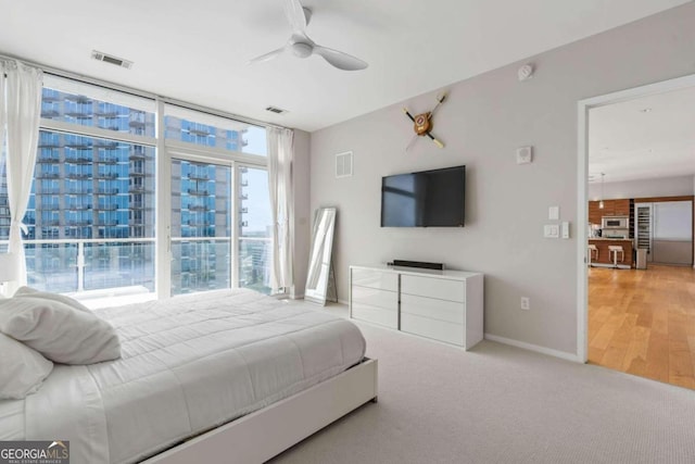 bedroom with visible vents, carpet, a wall of windows, and baseboards