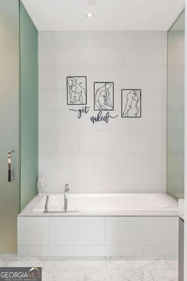 full bathroom with a garden tub and marble finish floor