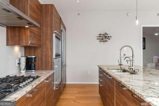 kitchen with a sink, modern cabinets, under cabinet range hood, and stainless steel gas cooktop