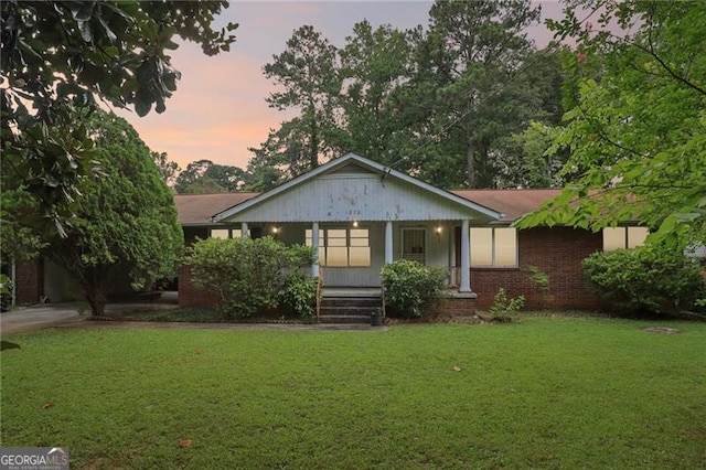 view of front of house featuring brick siding, a porch, and a lawn