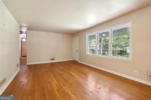 spare room featuring visible vents, baseboards, and wood finished floors