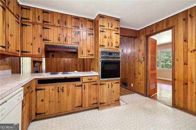 kitchen featuring wood walls, under cabinet range hood, white appliances, and light countertops