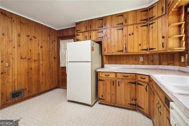 kitchen with sink, white appliances, wooden walls, and light tile patterned floors