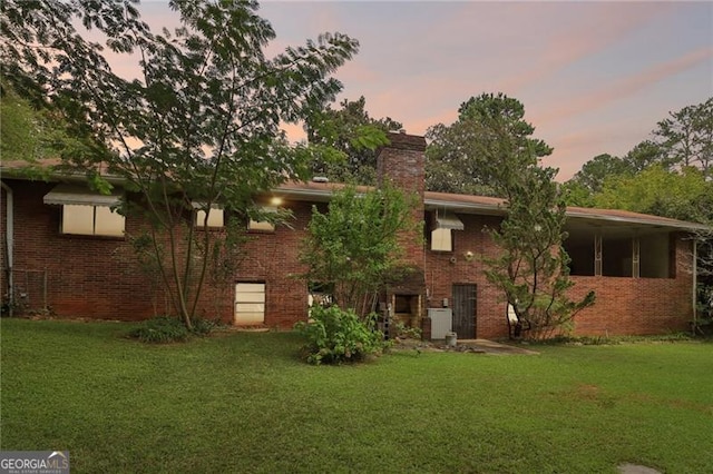 back house at dusk featuring a lawn