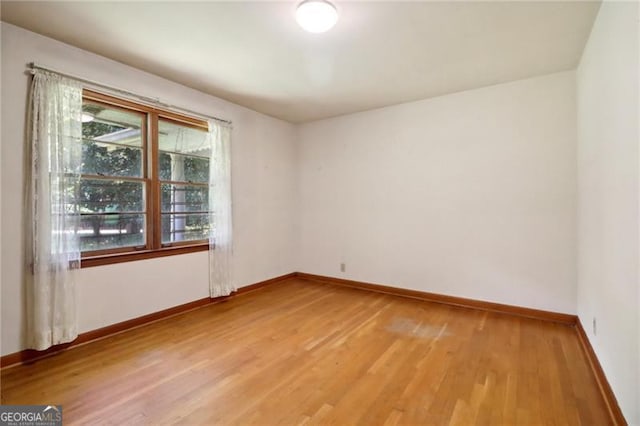 spare room featuring baseboards and light wood-style floors