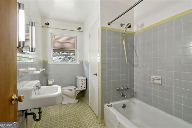 bathroom featuring tile walls, toilet, tiled shower / bath combo, and tile patterned floors