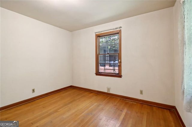 spare room featuring baseboards and light wood finished floors