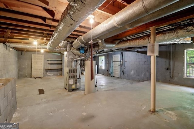 basement featuring concrete block wall and heating unit