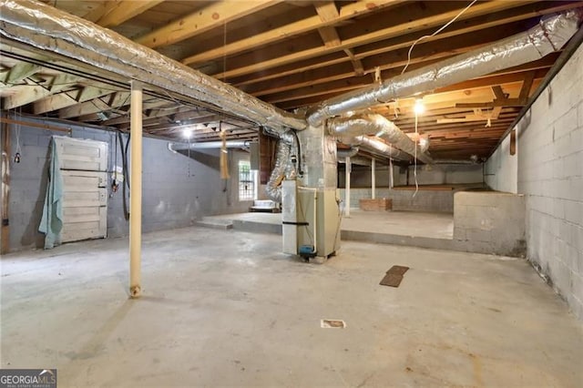basement featuring heating unit and concrete block wall