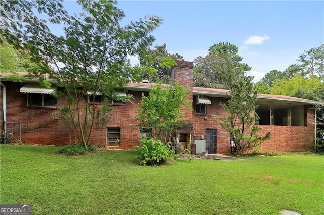 back of house featuring a yard, central AC, brick siding, and a chimney