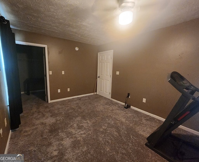 unfurnished bedroom with ceiling fan, a textured ceiling, carpet floors, and a walk in closet