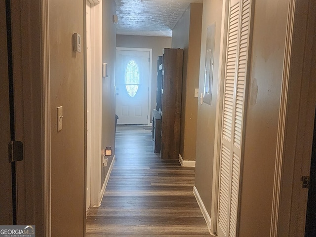 corridor with dark hardwood / wood-style floors and a textured ceiling