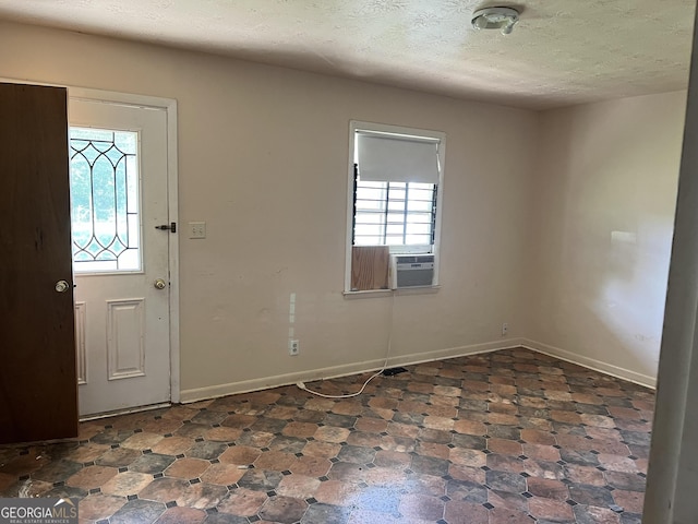 tiled entryway with a textured ceiling and cooling unit