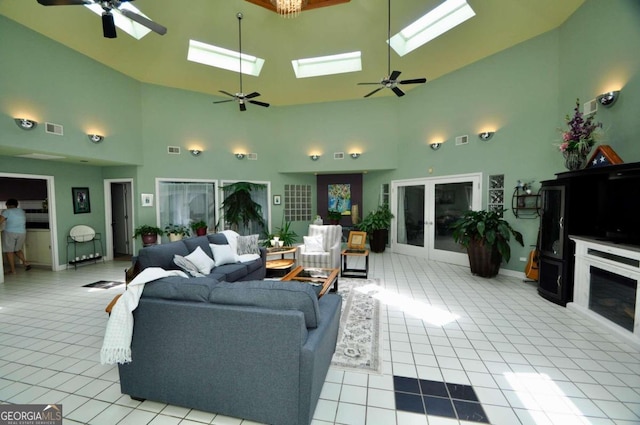 living room with a skylight, tile patterned flooring, visible vents, and ceiling fan