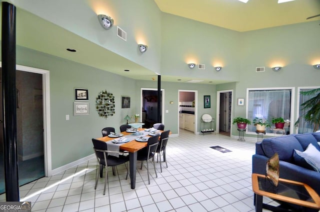 dining space with visible vents, a high ceiling, and light tile patterned floors