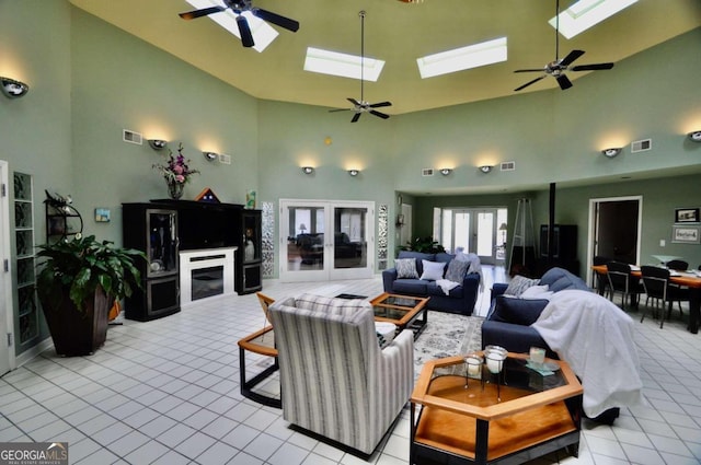 living area with light tile patterned floors, a high ceiling, a skylight, visible vents, and french doors