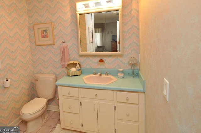 half bath featuring vanity, tile patterned floors, toilet, and wallpapered walls