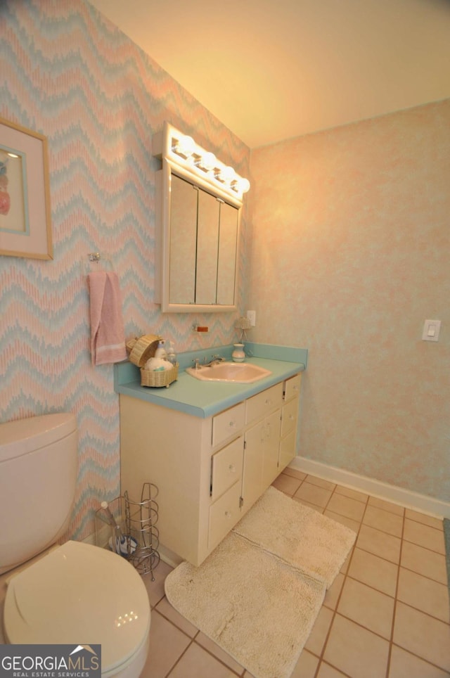 half bathroom with tile patterned flooring, toilet, vanity, and baseboards