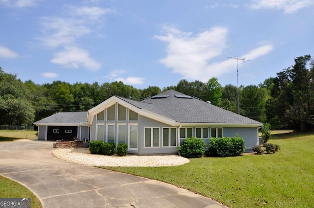 view of front of property with a garage, concrete driveway, a front yard, and stucco siding