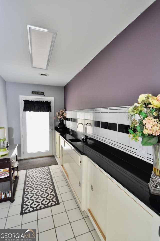 kitchen with tile countertops, light tile patterned floors, white cabinets, and a sink