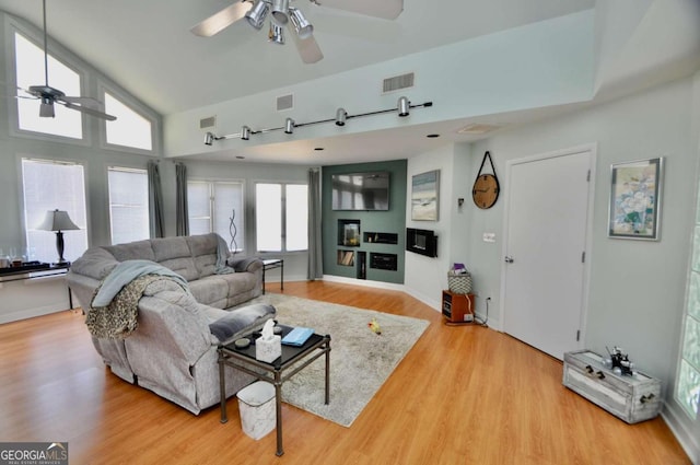 living room with light wood finished floors, visible vents, and a ceiling fan