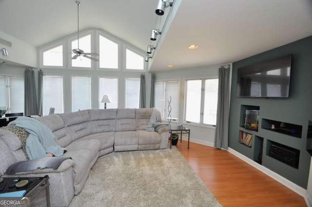 living area with baseboards, a ceiling fan, wood finished floors, vaulted ceiling, and a fireplace