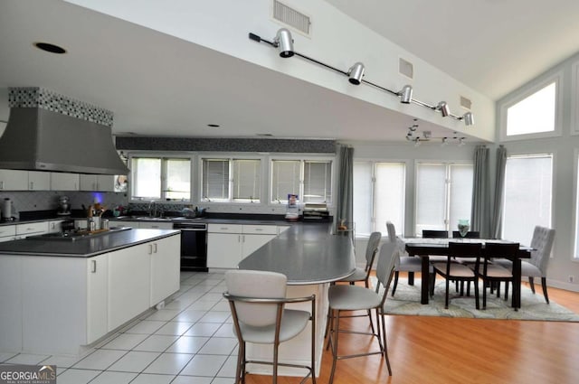 kitchen featuring extractor fan, white cabinets, black dishwasher, dark countertops, and cooktop