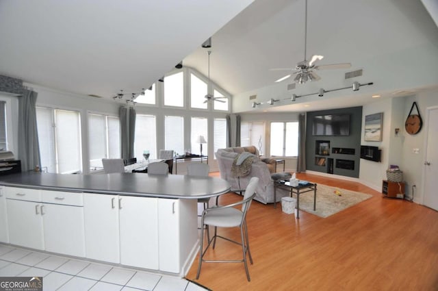 kitchen with visible vents, light wood-style floors, open floor plan, white cabinets, and ceiling fan