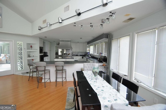 dining room with light wood finished floors, visible vents, and built in features