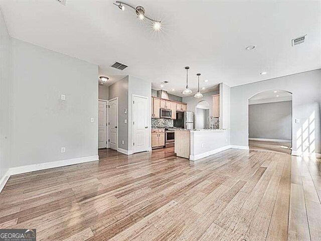 unfurnished living room featuring light wood-type flooring and sink