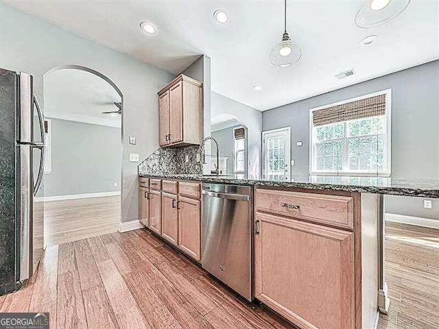 kitchen with ceiling fan, decorative backsplash, wood-type flooring, dark stone countertops, and stainless steel appliances