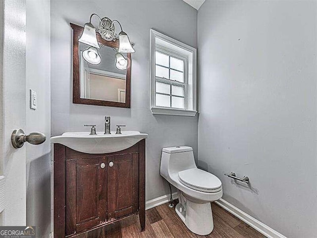 bathroom with hardwood / wood-style floors, toilet, and vanity