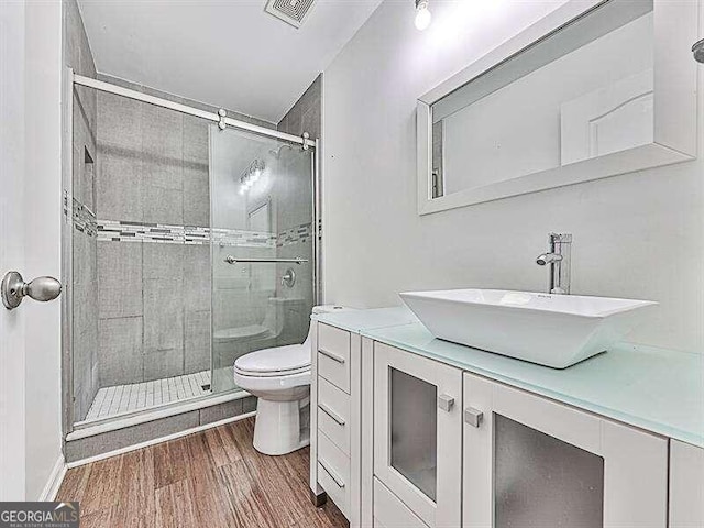 bathroom with a shower with door, toilet, vanity, and hardwood / wood-style flooring