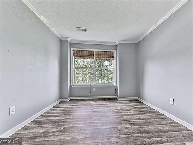 empty room featuring hardwood / wood-style floors, ornamental molding, and a textured ceiling